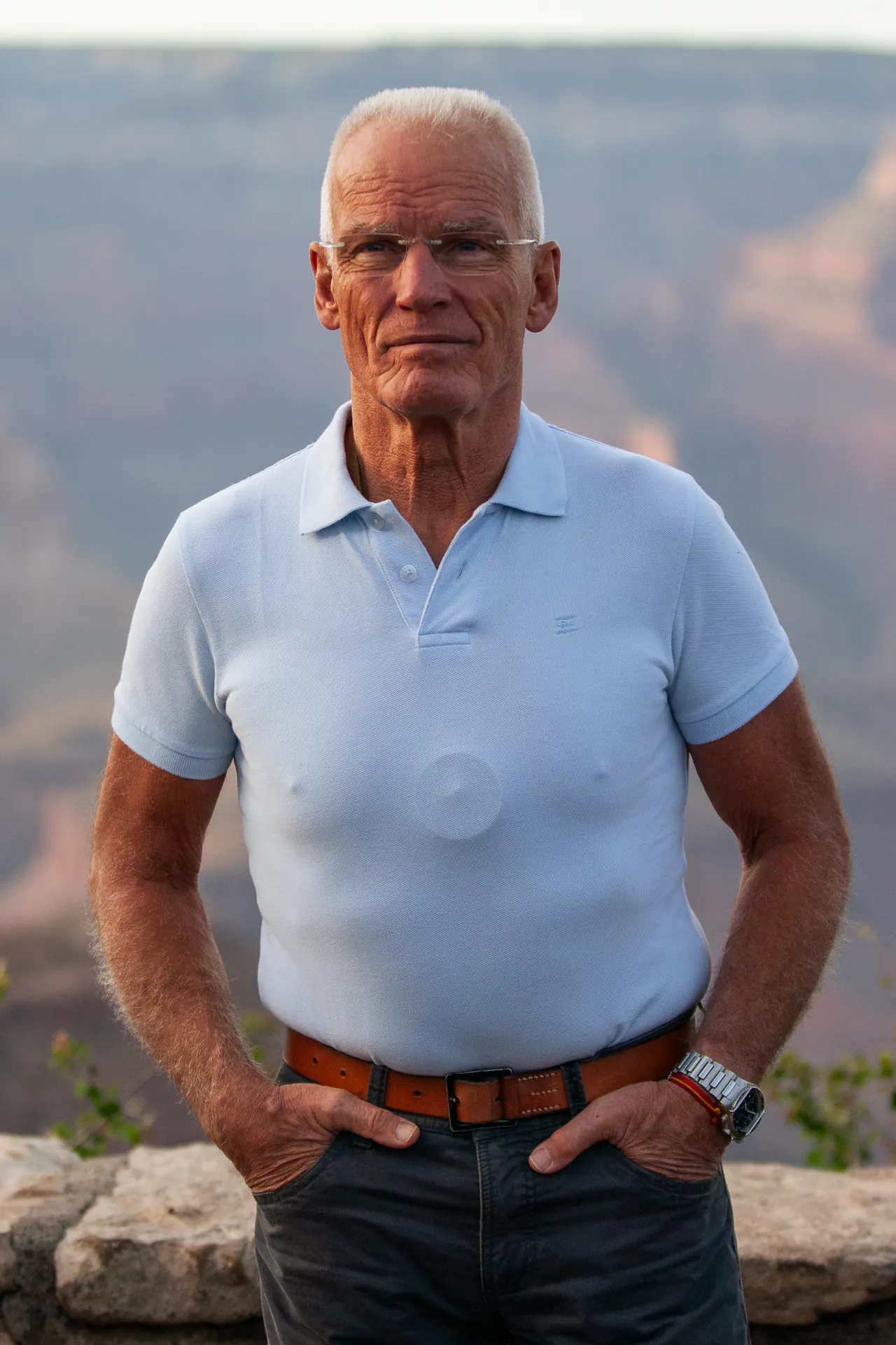 Lama Ole Nydahl stands with his hands at his belt, red canyon walls rising behind him