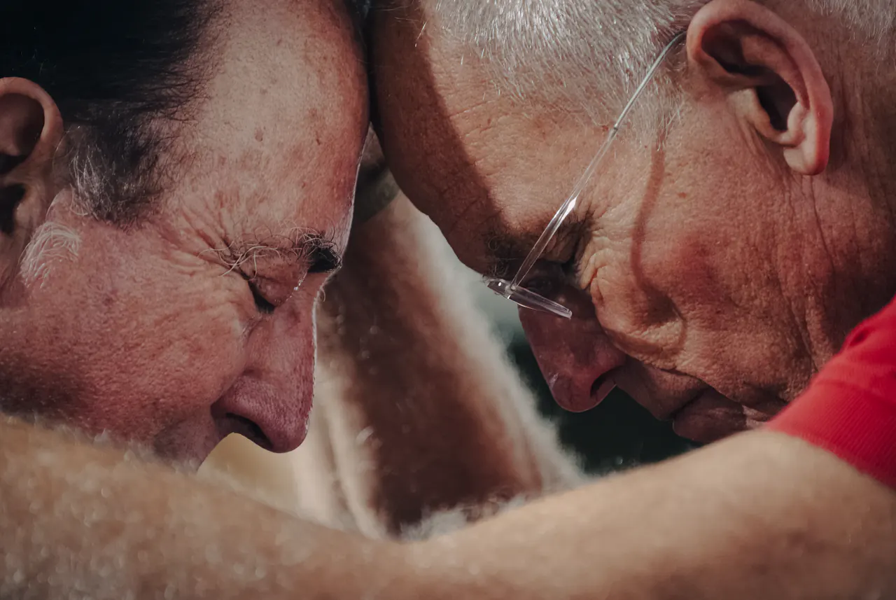 Close-up of two faces meeting forehead to forehead, glasses pressed between them