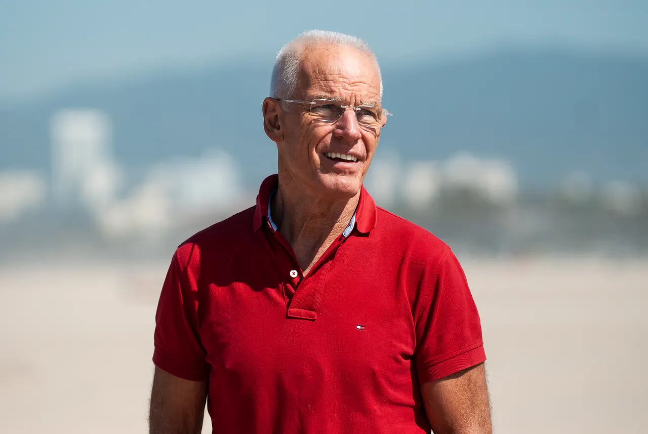 Lama Ole Nydahl smiles on the beach in a red polo shirt