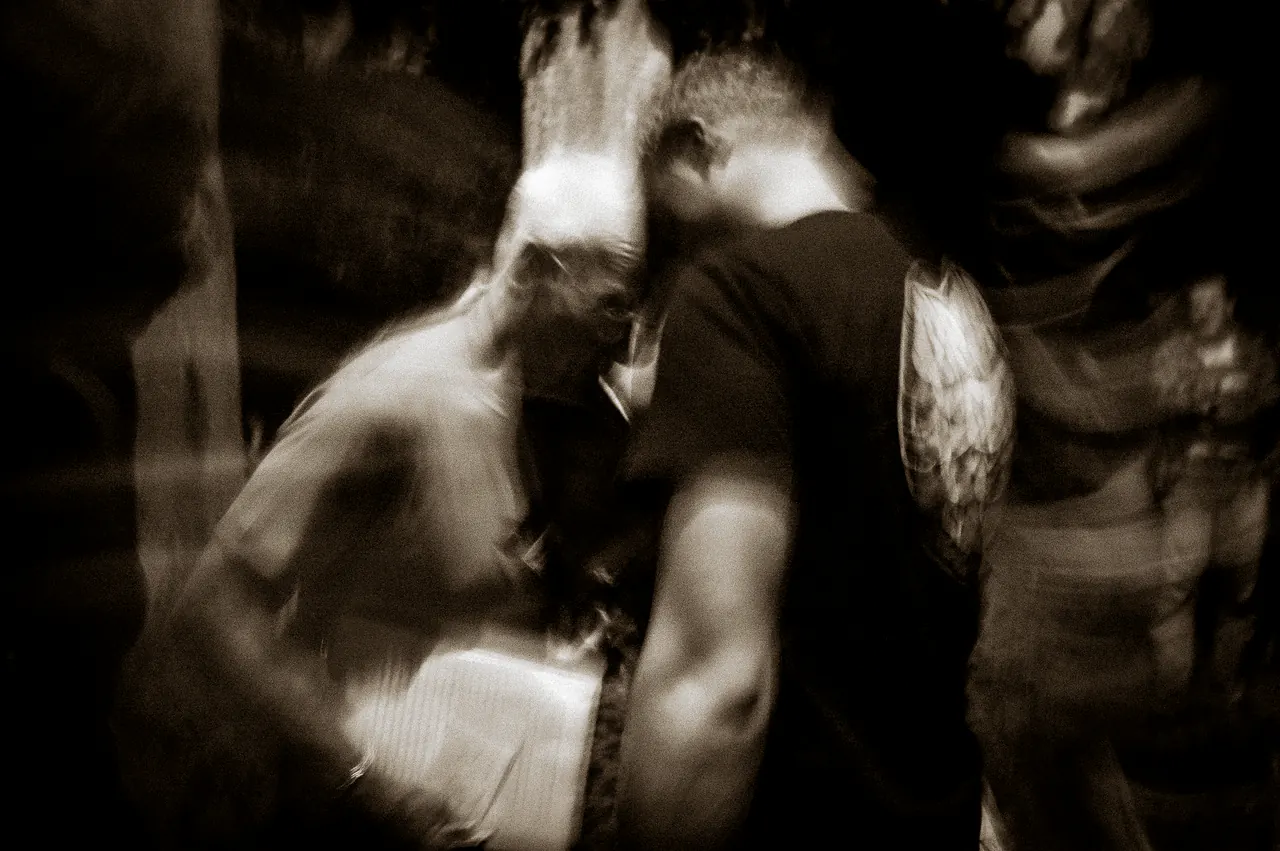 A blurred sepia exposure of Lama Ole Nydahl leaning over people, the movement smeared across the frame