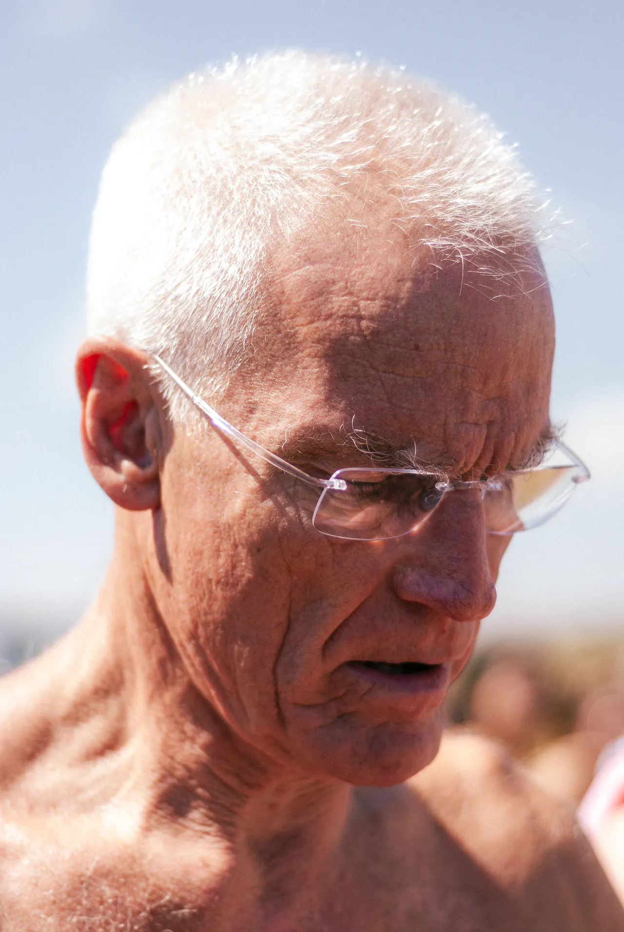 Close portrait of Lama Ole Nydahl bare-chested on the beach, his eyes lowered