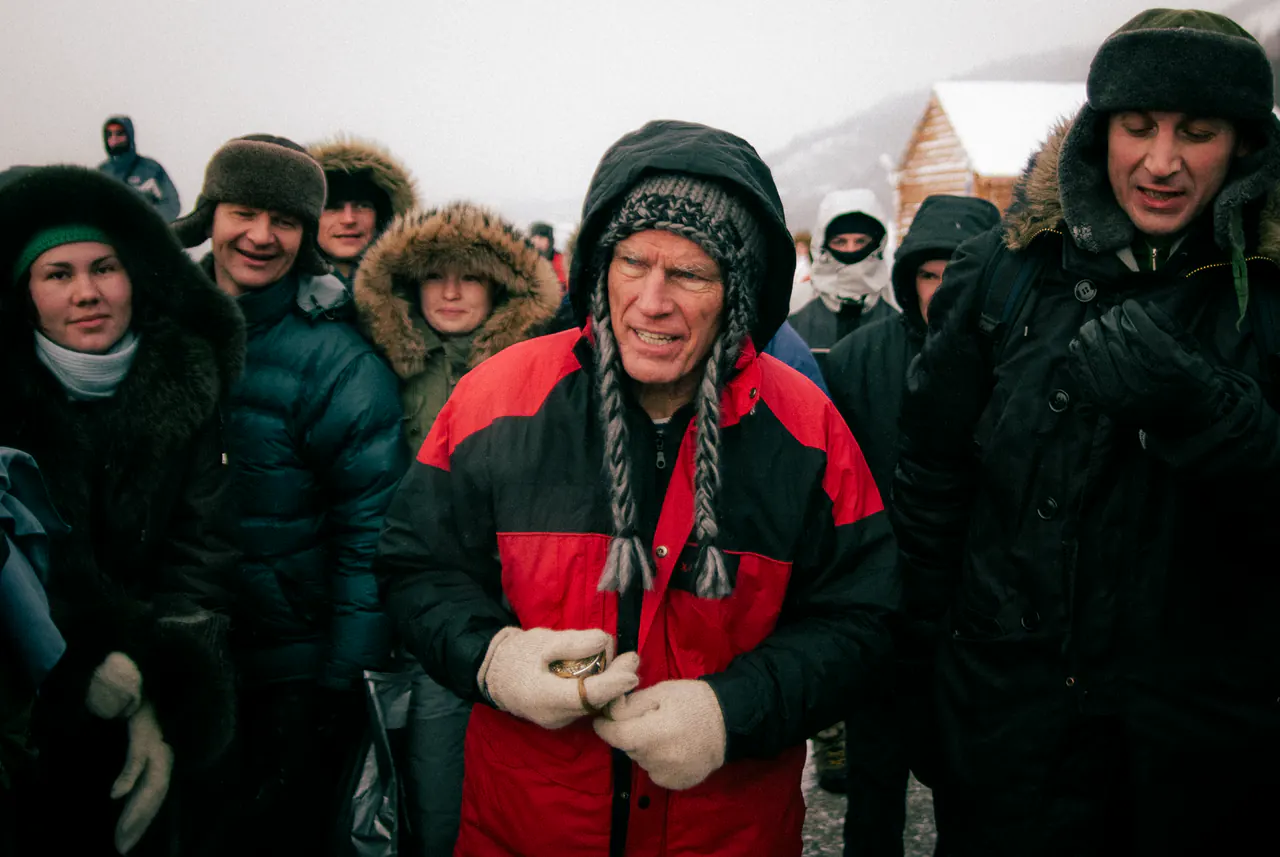Lama Ole Nydahl stands in the snow in a fur hat with ear flaps, people in heavy coats around him