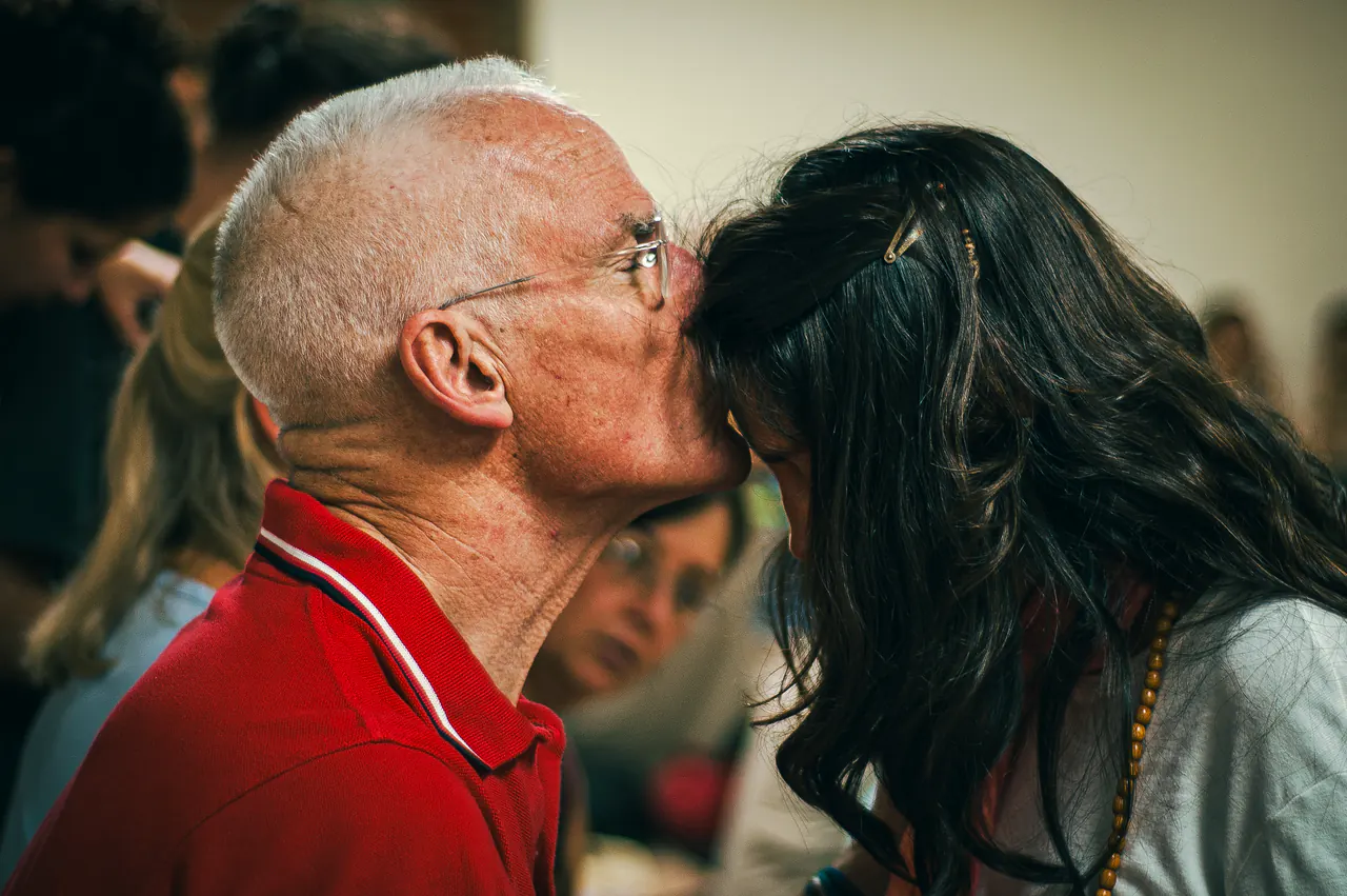 Lama Ole Nydahl presses his forehead to a woman's forehead in a crowd