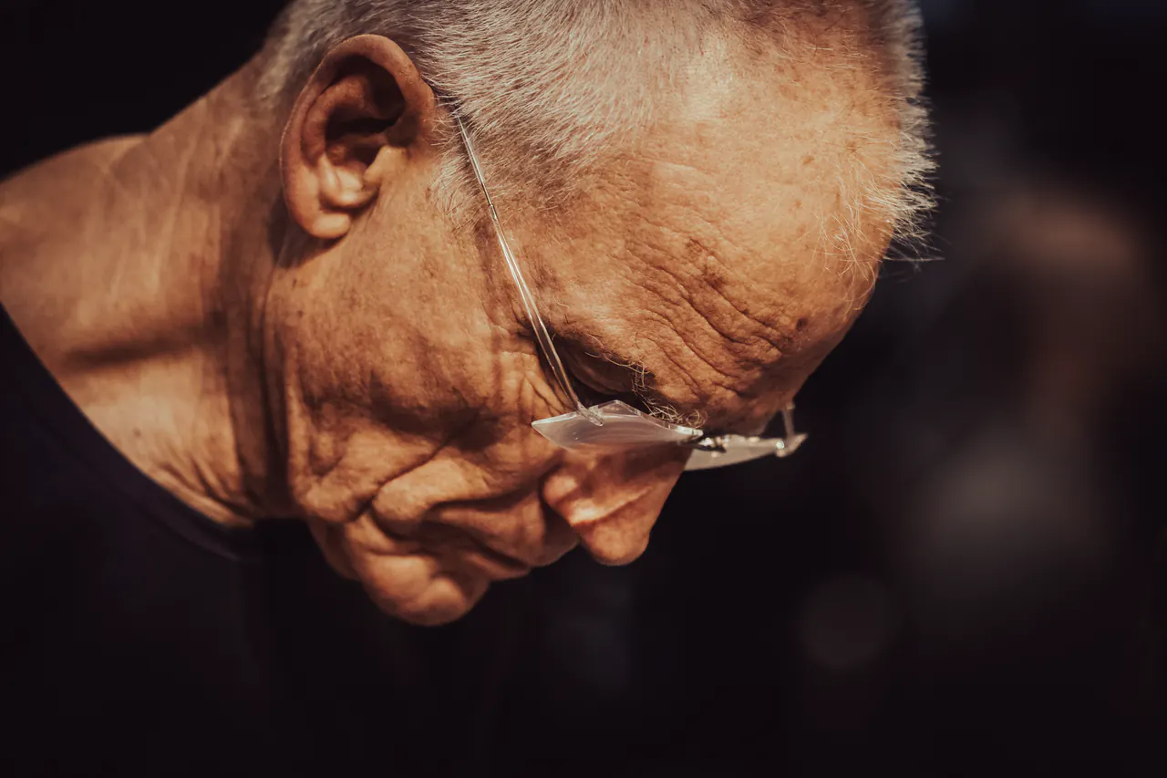 Close-up of Lama Ole Nydahl with his head bowed, glasses low on his nose