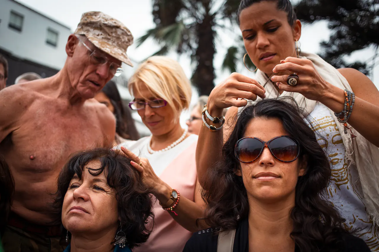 In a camouflage cap, Lama Ole Nydahl reaches over a crowd to touch a woman's head