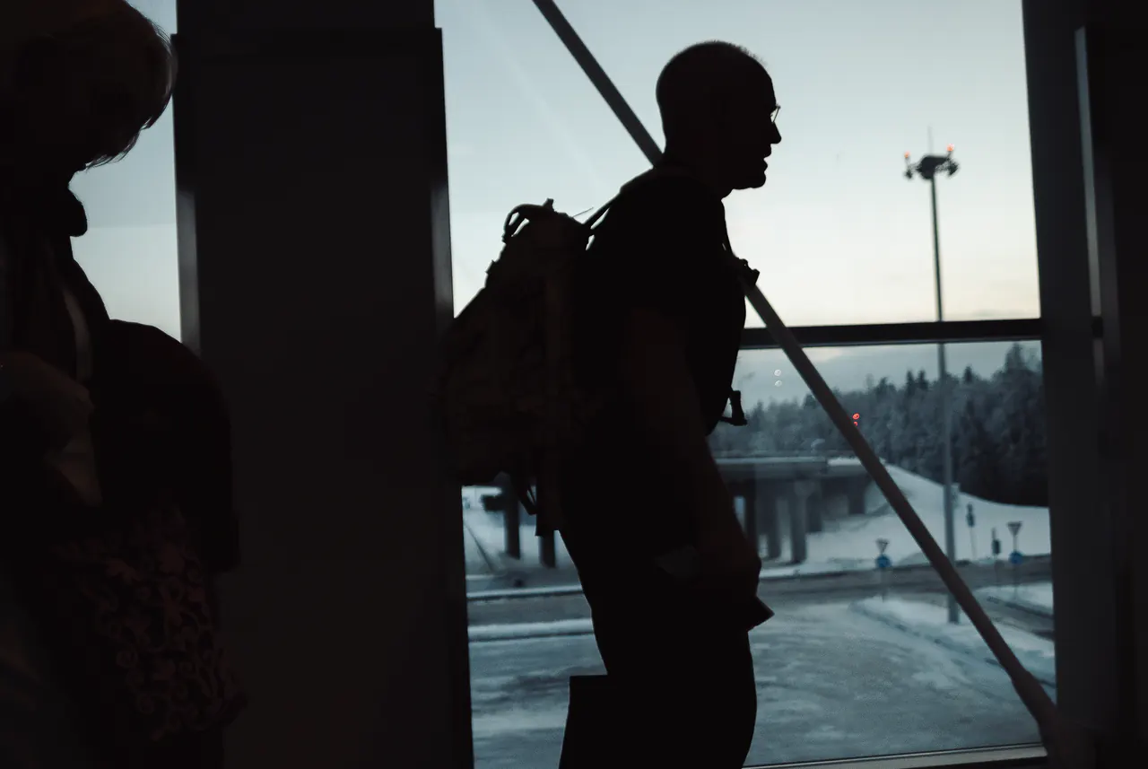 Silhouetted against a station window, Lama Ole Nydahl waits with a backpack