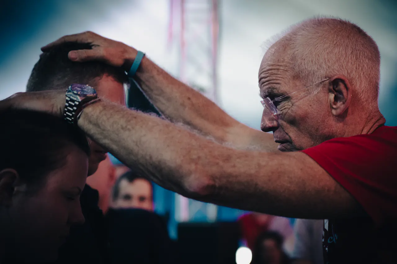 Lama Ole Nydahl lays both hands on the head of a person bowing in front of him